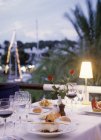 Накрытый стол с морепродуктами, напитками и цветами в вечернем свете — стоковое фото