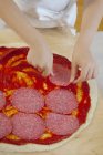 Fille mettre du salami — Photo de stock
