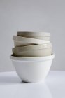 Vista de cerca de los recipientes de cerámica apilados surtidos en la superficie blanca - foto de stock