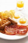 English breakfast with orange juice on white plate with eggs, meat and beans — Stock Photo
