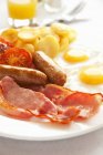 Closeup view of English breakfast with sausages, bacon, fried eggs and vegetables — Stock Photo
