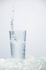 Closeup view of ice cube splashing in glass of Ouzo — Stock Photo