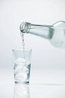 Versare la vodka in un bicchiere contenente cubetti di ghiaccio — Foto stock