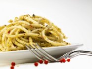 Espaguetis con pesto y granos de pimienta rosa - foto de stock