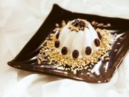 Vista ravvicinata di vaniglia Blancmange con chicchi di caffè ricoperti di cioccolato e noci tritate — Foto stock