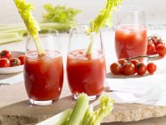 Closeup view of Bloody Mary cocktails with celery and tomatoes — Stock Photo