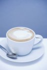 Cappuccino sul piatto con cucchiaio — Foto stock