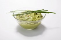 Guacamole in un piatto con erba cipollina su sfondo bianco — Foto stock