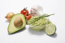 A dish of guacamole with ingredients on white background — Stock Photo