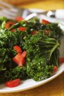 Fresh Sauteed Kale with Chopped Red Pepper  on white plate — Stock Photo