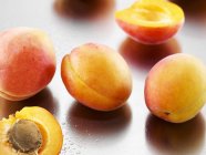 Mehrere Aprikosen, ganz und halbiert — Stockfoto