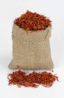 Stoffsack mit getrockneten roten Safranblütenblättern auf weißer Oberfläche — Stockfoto