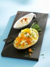 Baked potato with keta caviar and chives on black deskover blue surface — Stock Photo