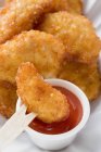 Closeup view of dipping chicken nugget into ketchup with wooden fork — Stock Photo