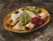 Крупный план мексиканской комбинированной тарелки с обертываниями, соусами и лимонными клиньями — стоковое фото