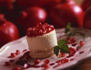 Гранатовый десерт на белой тарелке на размытом фоне — стоковое фото
