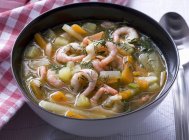 Garnelensuppe mit Gemüse und Dill auf schwarzer Schüssel über dem Tisch — Stockfoto