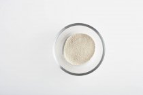 Top view of a glass bowl of dried yeast on white background — Stock Photo