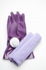 Vue rapprochée des gants en caoutchouc violet avec brosse et serviette sur la surface blanche — Photo de stock