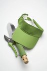 Elevated view of garden tools and green cap on white surface — Stock Photo