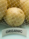 Organic potatoes in net bag — Stock Photo