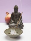 Vista de cerca de la varilla de incienso en plato de cerámica con figura de Buda y granada - foto de stock