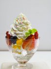 Closeup view of mixed fruit on ice cubes with whipped cream — Stock Photo