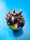 Closeup view of Gooseneck barnacles with ice, lime and herb in bowl on blue wet surface — Stock Photo