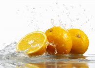Апельсины с брызгами воды — стоковое фото