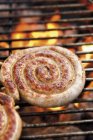 Saucisse enroulée sur grille barbecue — Photo de stock