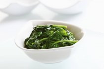 Blanched spinach in ceramic bowl on white background — Stock Photo