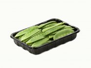 Mangetout in a plastic tray  on white background — Stock Photo