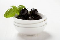 Schwarze Oliven und Basilikumblätter — Stockfoto