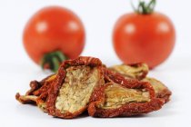 Getrocknete Tomaten vor frischen Tomaten — Stockfoto