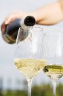 Hand Pouring white wine into glass — Stock Photo