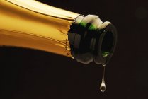 Sparkling wine dripping out of bottle — Stock Photo
