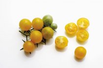 Tomates amarillos enteros y cortados a la mitad - foto de stock