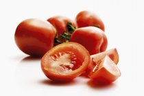 Tomates roms entières et coupées en deux — Photo de stock