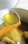 Ladle of chicken broth over pot of soup — Stock Photo