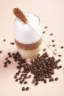 Nahaufnahme geschichteter Latte mit Zuckerstange und Kaffeebohnen — Stockfoto