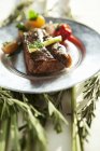 Steak on plate over herbs — Stock Photo