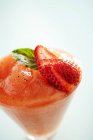 Vista close-up de purê de frutas com fatias de morango e folha verde em vidro — Fotografia de Stock