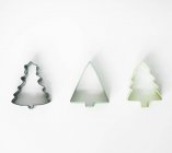 Closeup view of three different shaped tree cookie cutters on white surface — Stock Photo