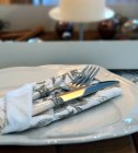 Messer und Gabel in einer gemusterten Serviette auf einem Teller — Stockfoto