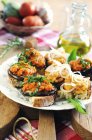 Mixed Tuscan crostini in white plate over wooden desk on table — Stock Photo