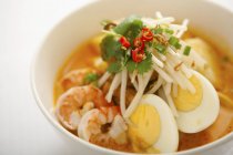 Nahaufnahme malaiischer Nudeln mit gekochten Eihälften, Garnelen und Kräutern — Stockfoto