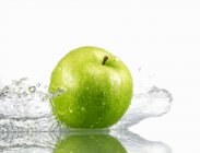 Зеленое яблоко с брызгами воды — стоковое фото