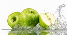 Зеленые яблоки целые и наполовину — стоковое фото