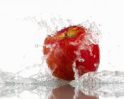 Красное яблоко с брызгами воды — стоковое фото