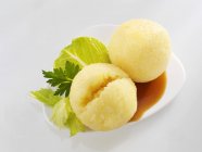 Kartoffelknödel mit Soße auf weißem Teller vor weißem Hintergrund — Stockfoto